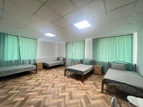 a hospital room with three beds and green curtains at Мотель 32 in Aktobe