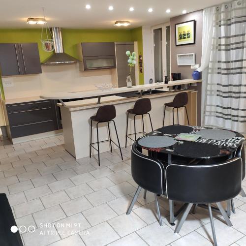 une cuisine avec une table et des tabourets dans une pièce dans l'établissement MEUBLE Centre Epinal SCI FLYM, à Épinal