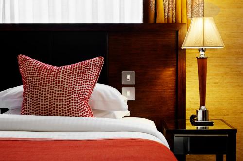 a bedroom with a bed with a red pillow and a lamp at The Mandeville Hotel in London