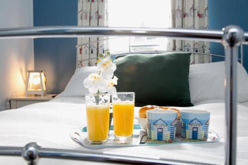 a tray with two glasses of orange juice and food on a bed at Cosy seaside cottage in Criccieth