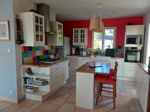une cuisine avec des placards blancs et un mur rouge dans l'établissement Family home Les Collines, à Bègues
