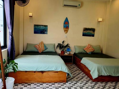 a bedroom with two beds and a surfboard on the wall at Sông Suối homestay 2 in Quy Nhon