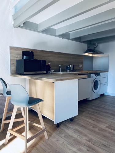 une cuisine avec un comptoir, une chaise et un four micro-ondes dans l'établissement Apartment for 4 with balcony near the Old Port, à La Rochelle
