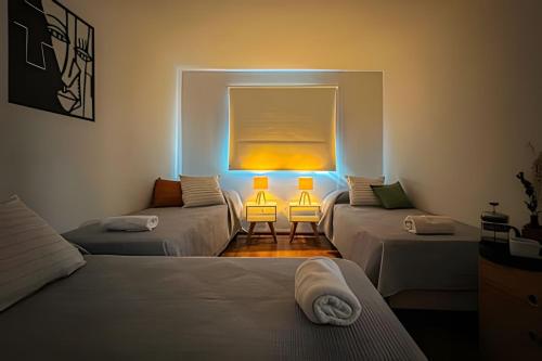 a room with three beds and a window with lights at Hermosa Casa, Chacras de Coria-Pileta-Parrilla-AA in Ciudad Lujan de Cuyo