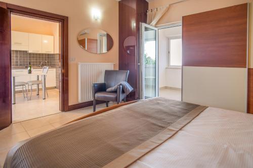 a bedroom with a bed and a chair and a kitchen at Villa Palma in Malinska