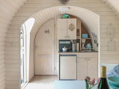 an archway in a kitchen with a sink and a refrigerator at Iglucraft Tiny Haus im Naheland I Grill I Wasserspielpatz I W-LAN in Heddesheim