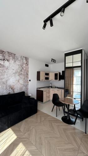 a living room with a black couch and a table at Apartament Charisma in Giżycko