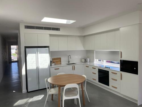a kitchen with a wooden table and a refrigerator at Coastal 3 bedroom duplex Everything at your doorstep in Towradgi