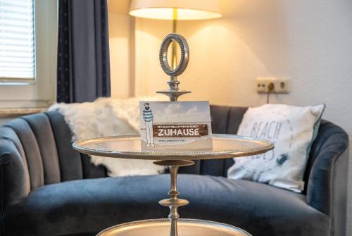 a table with a book and a mirror on a couch at HOTEL DÜNENLÄUFER Langeoog in Langeoog