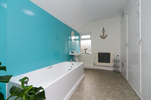 a bathroom with a white tub and a blue wall at 6 Afallon, Beachside holiday house in Criccieth