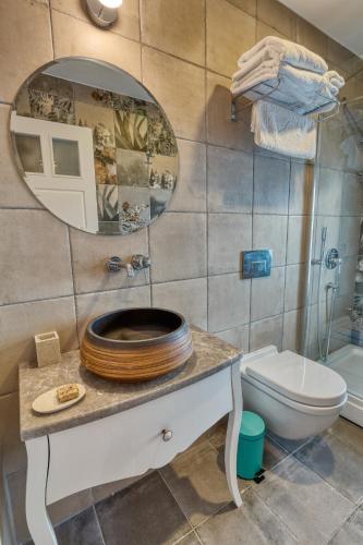 a bathroom with a sink and a mirror and a toilet at Sigacik Gardenya Buti̇k Otel in Siğacık