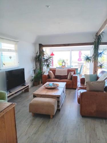 a large living room with couches and a tv at 216 Coast Road, Ocean Bliss Direct Beach Access & Endless Waves in Pevensey