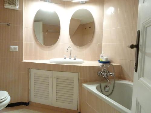 baño con lavabo, aseo y 2 espejos en La Casa del Faro, en Porto Ercole