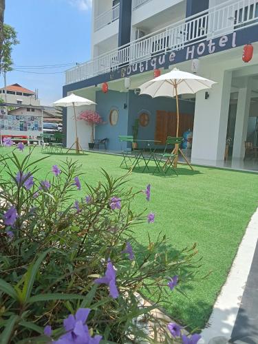 a hotel with purple flowers in front of a building at J-Boutique Hotel เจ-บูทีค โฮเทล in Khon Kaen