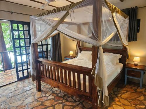 a bedroom with a canopy bed with white pillows at Nile river cottages in Jinja