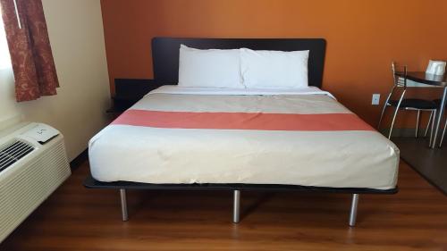 uma cama num pequeno quarto com uma média de atronatronatronstrationstration em Motel 6 Maple/Main em Hesperia