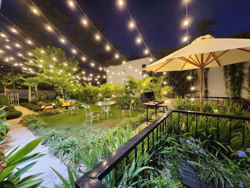 a patio with an umbrella and tables and chairs at VILLA VENUS -Khu B Không mất vé cổng - tại Khu du lịch sinh thái Đại Lải in Thanh Cao