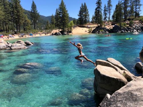 a woman jumping off rocks into a river at Experience Zephyr Cove Retreat Relax Enjoy #6 in Zephyr Cove