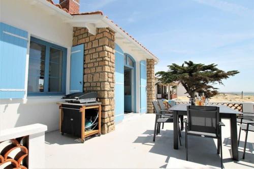 un patio avec une table, des chaises et un barbecue dans l'établissement RARE Villa bord de mer, à La Tranche-sur-Mer