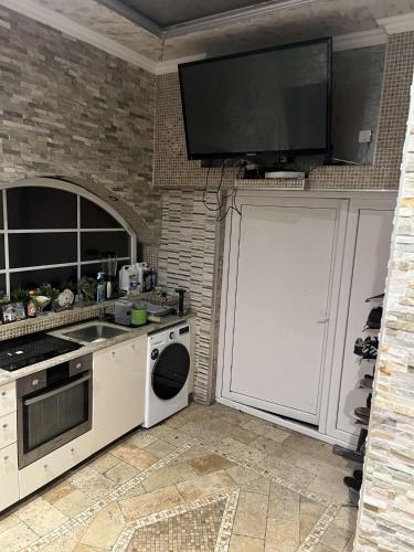 une cuisine avec une télévision au-dessus d'un mur dans l'établissement Le foyer des gourmands, à Saint-Fons