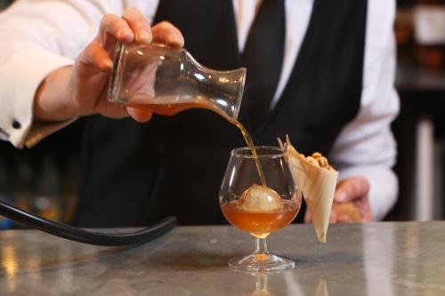 a man pouring a drink into a glass at The Mandeville Hotel in London
