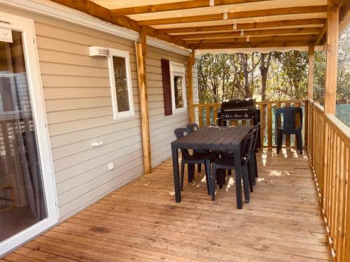 une terrasse couverte en bois avec une table et des chaises. dans l'établissement Mobil Home Oliviers 4, à Valras-Plage