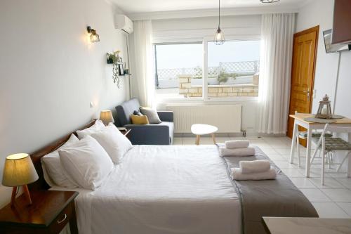 a bedroom with a white bed and a living room at Ionian Blue Studio in Preveza