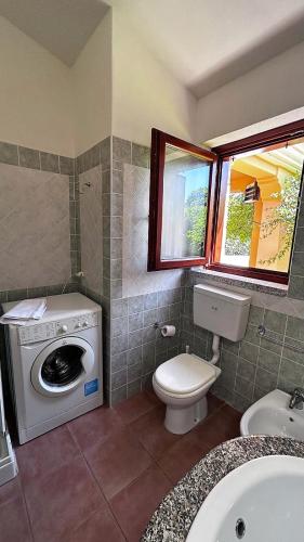 a bathroom with a washing machine and a toilet at CASA PISCINA Fois in San Teodoro