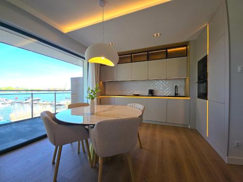 a kitchen and dining room with a table and a view at Marina Ostróda IV - super widok na jezioro, 10 m do wody, taras i balkon, winda, klima, garaż in Ostróda