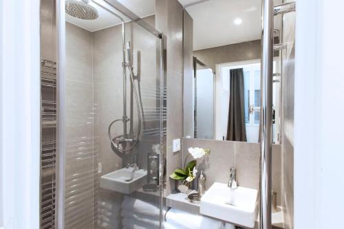 une salle de bain avec deux lavabos et une douche dans l'établissement Charming 2BR-2BA between le Marais & le Louvre, à Paris