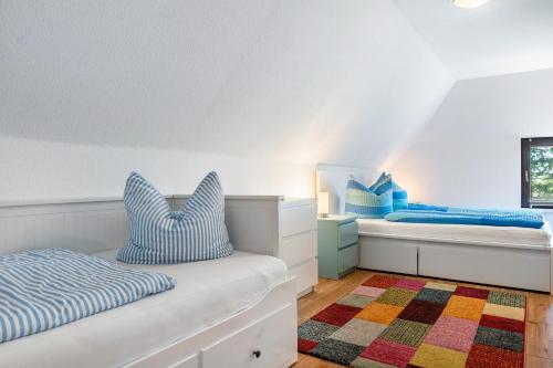 a white bedroom with two beds and a rug at Ferienwohnung 3 in Groß Zicker
