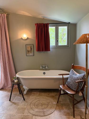 une salle de bain avec une baignoire, une chaise et une fenêtre dans l'établissement Chateau de Pomiro chambres d'hôtes et gîte, à Montréal