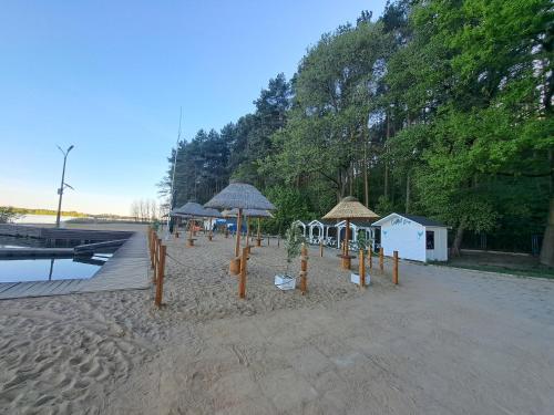 a sandy beach with umbrellas and chairs and a building at Słoneczny Zakątek nad Narwią in Serock
