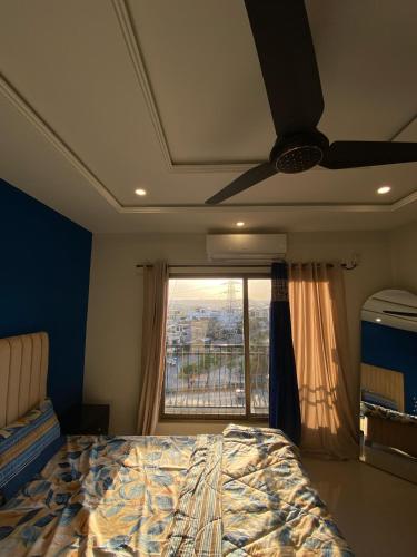 a bedroom with a ceiling fan and a bed with a window at Raajgan Loft in Rawalpindi