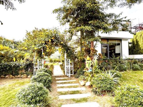 a garden with an arch and a path leading to a house at VILLA VENUS -Khu B Không mất vé cổng - tại Khu du lịch sinh thái Đại Lải in Thanh Cao