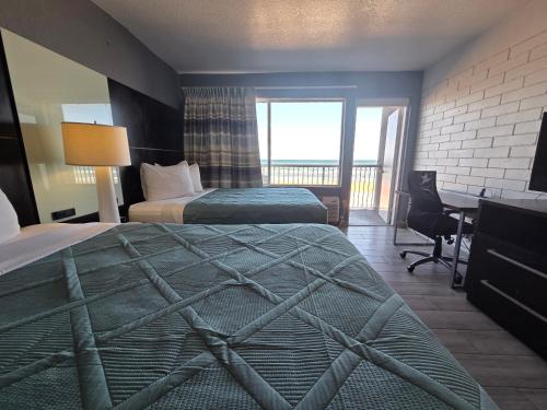 a hotel room with two beds and a desk at Beach House Inn in Daytona Beach