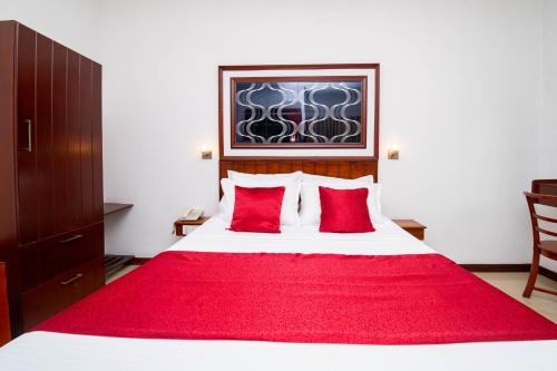 a bedroom with a large bed with red pillows at Colour Moon Hotel in Kotagala
