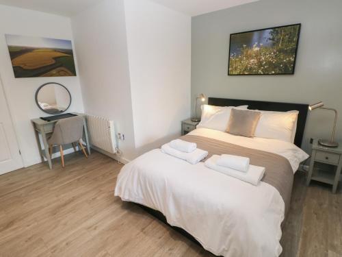 a bedroom with a large bed with two towels on it at Sycamore in Cowbridge