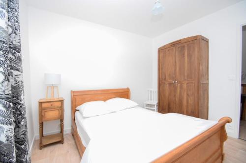 une chambre avec un lit et une armoire en bois dans l'établissement Maison de la mer à 6min des plages avec jardin, à Saint-Coulomb