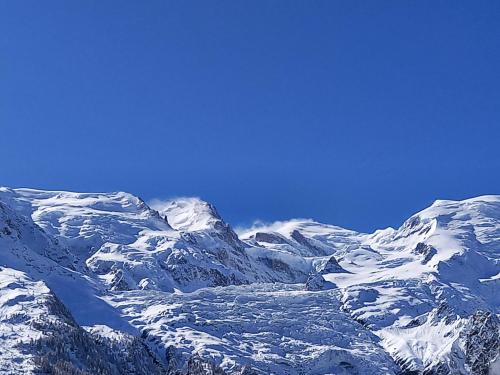 a snow covered mountain range with a blue sky at Appartement avec Terrasse in Chamonix-Mont-Blanc