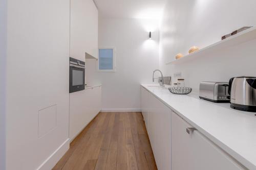Il comprend une cuisine blanche avec des placards blancs et du parquet. dans l'établissement Beautiful Duplex Heart of Paris, à Paris