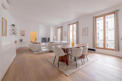 un salon blanc avec une table et des chaises dans l'établissement Beautiful Duplex Heart of Paris, à Paris