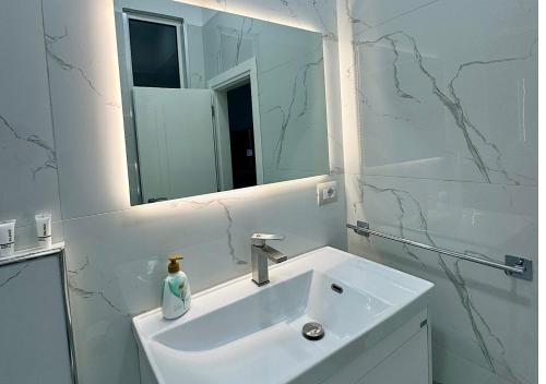 a white bathroom with a sink and a mirror at Hotel Krial in Berat