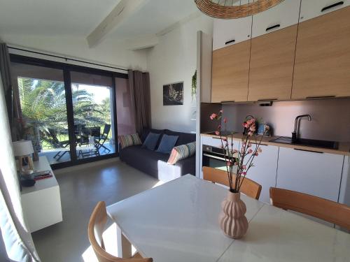 une cuisine et un salon avec une table et un canapé dans l'établissement Joli appartement Les Parcs de Grimaud - Piscine, à Grimaud