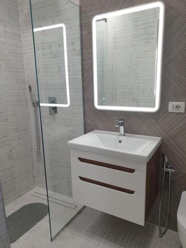 un bagno con lavandino, doccia e specchio di Adas apartment a Vlorë