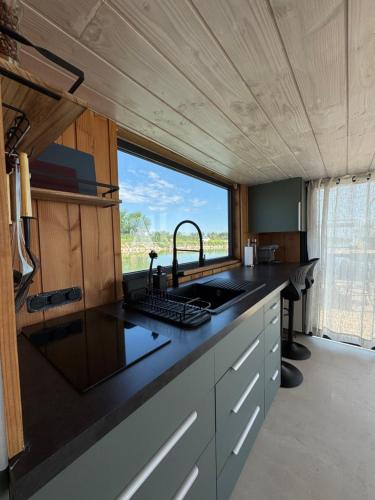 a kitchen with a sink and a large window at La cabane a fleur d eau au cœur de la Camargue in Saint-Gilles