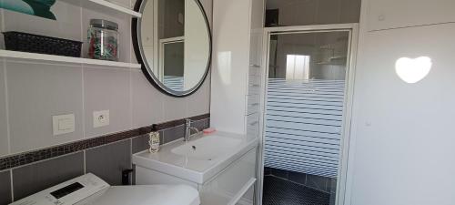 une salle de bain blanche avec un lavabo et un miroir dans l'établissement Charmante maisonnette proche plage, à Châtelaillon-Plage