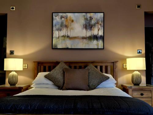 a bedroom with a bed with two lamps and a painting at The Badger Inn in Church Minshull