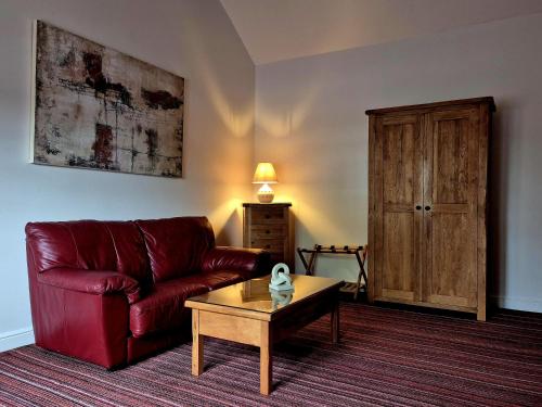 a living room with a red couch and a coffee table at The Badger Inn in Church Minshull