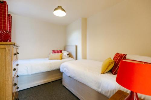 a bedroom with two beds with red and yellow pillows at James Ville Marina, Lodge 9 in Brigg